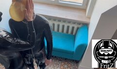 a latex slave tied up with a breathing mask and a blowjob