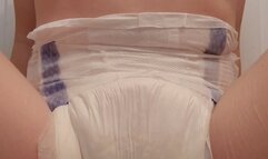 Pinkie wets her diaper while sitting on a mat