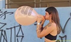 Maya Blows to Pop Two Printed Balloons