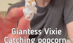 Giantess Vixie catching popcorn in her giant mouth with Tiny Man inside