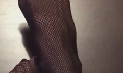 Sexy tiny feet with long toes in black fishnet legs in the air