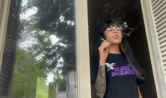 smoking absent-mindedly at the window