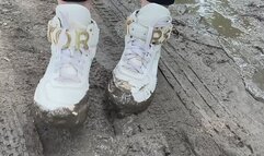 A girl in fashionable snow-white sneakers He walks on slippery, sticky mud and gets his hands dirty and crush her sneakers