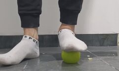 Apples being crushed by male feet in white socks