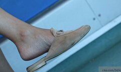 Candid beauty feet in and crossed legs in a slippers dangling