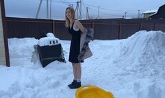 girl walks barefoot in the snow and slides down the hill