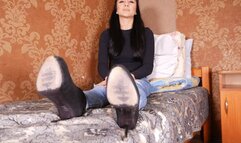 The beauty sits on the bed and shows off her gorgeous heels