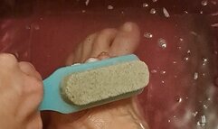Scrubbing feet and toes with a soapy brush