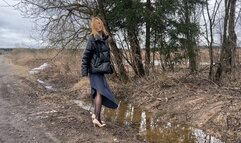 girl in high-heeled shoes walks along a wet and dirty road, dirtying her shoes and stockingsR