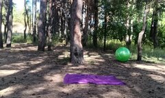 girl jumping on green ball in forest